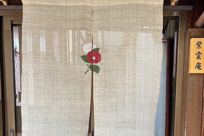 Una pantalla tradicional japonesa shoji con un diseño de flor roja, un marco de puerta de madera y un letrero con caracteres japoneses. 4