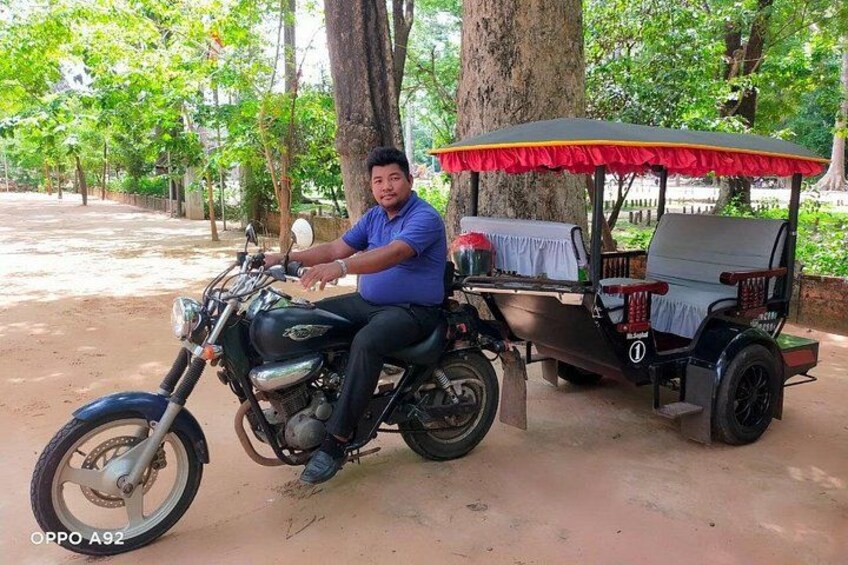 A man sitting on a motorcycle with a sidecar, parked under a red umbrella. 3