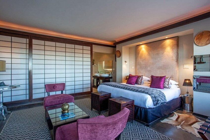 A modern hotel room with a large bed, a sitting area with a table, and traditional Japanese sliding doors. 2