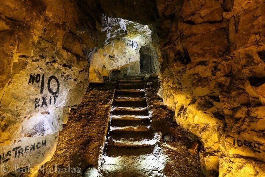 A stone staircase leading to an exit in a cave, with 'NO 10 EXIT' and 'NO EXIT' signs visible. 2