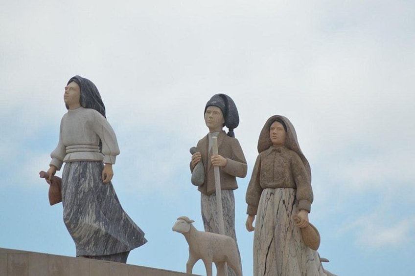 Tres estatuas de personas con animales, sobre un cielo nublado. 5