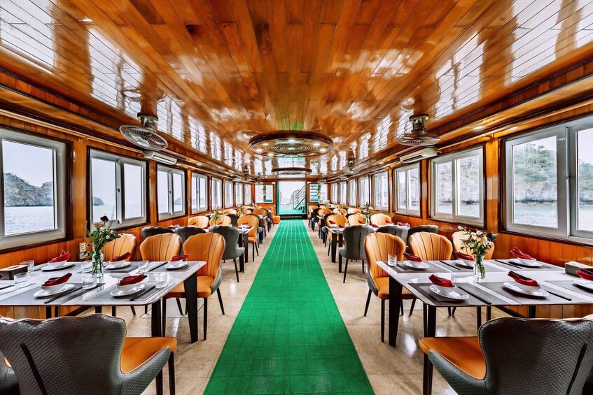 A dining area with wooden walls, large windows, and a green carpet. 5