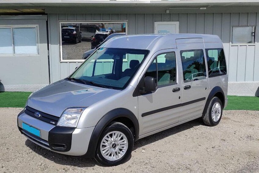 A silver van parked in front of a building with a gravel driveway. 3