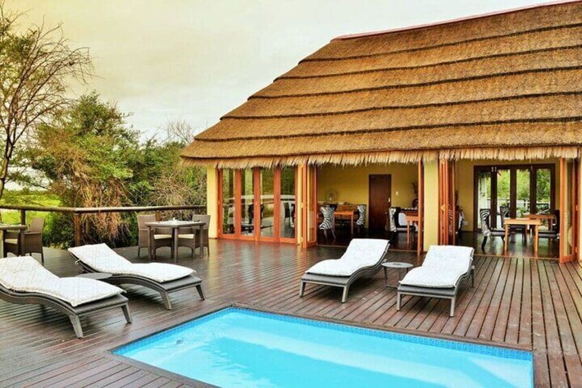 A poolside area with lounge chairs and a thatched-roof structure. 1