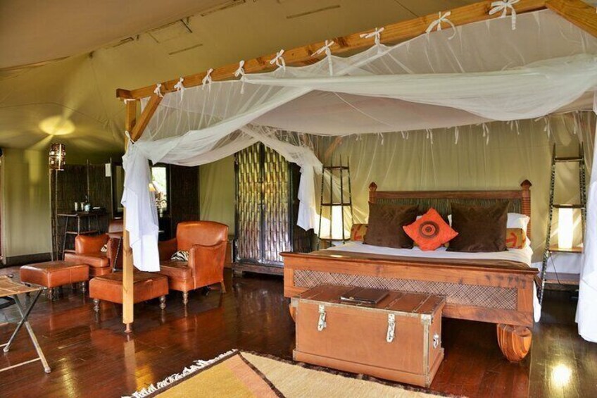 A room with a bed under a canopy, wooden furniture, and a suitcase. 2