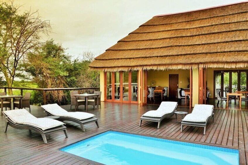 A poolside area with lounge chairs, a thatched-roof structure, and a view of the surrounding landscape. 4