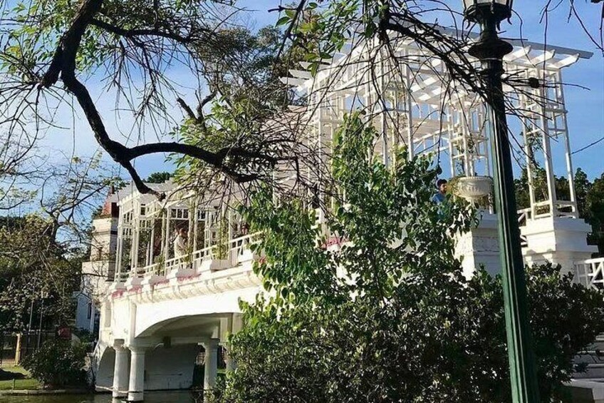 Un edificio blanco con balcón, rodeado de árboles y un farol. 3