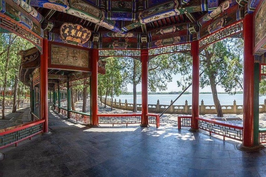 En traditionell paviljong med en detaljrikt utformad takkonstruktion, en stenlagd gång och utsikt över en vattenyta. 3