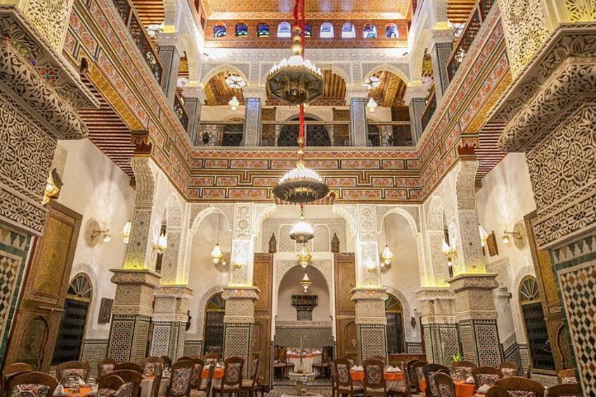 An ornate interior with intricate tile work, arches, and hanging lamps. 2