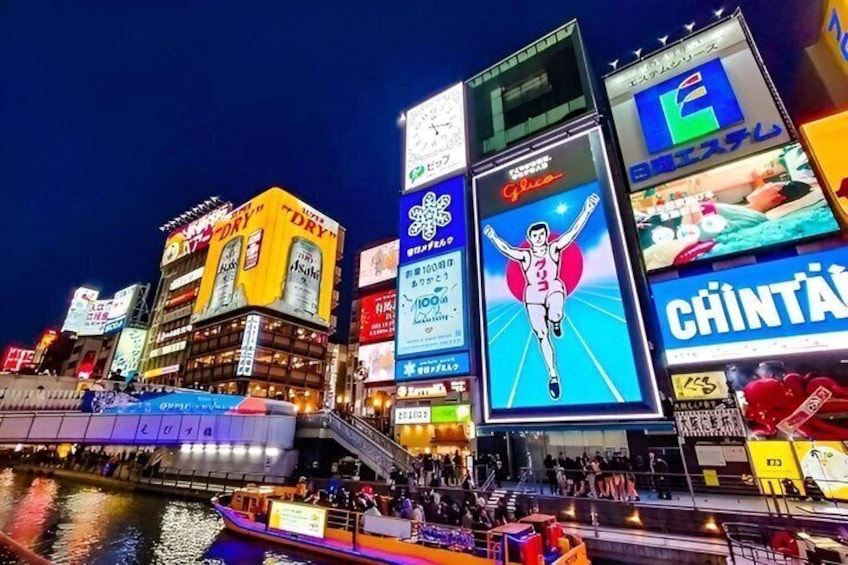 A brightly lit urban area with illuminated billboards and a river. 2