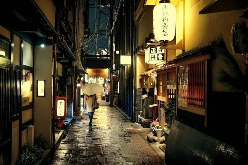 A narrow alley with traditional Japanese signage and a person walking with an umbrella. 3