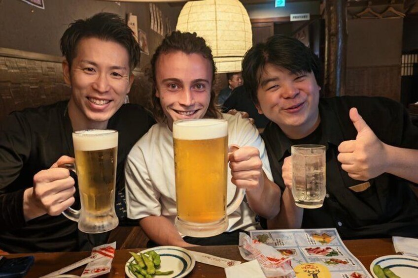 Three people at a restaurant table with beer glasses and a menu. 1