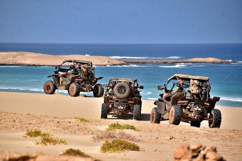Off-road vehicles on a beach with the ocean in the background. 1