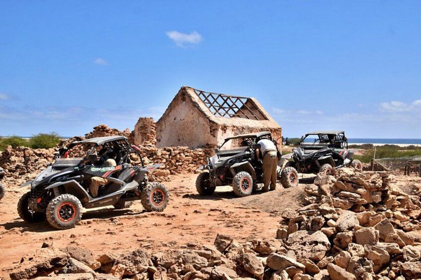 Off-road vehicles, a thatched-roof structure, and a rocky terrain. 2