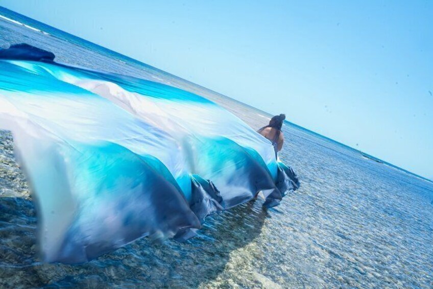 A person walking on a beach with a flowing fabric. 3