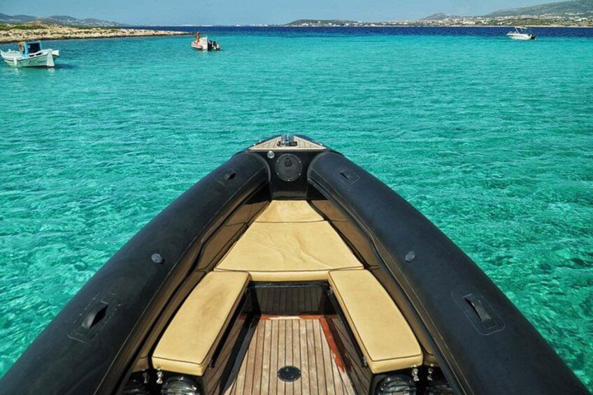 A boat on clear turquoise water with a wooden deck and a view of the coastline. 2