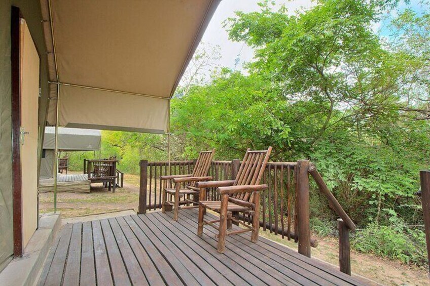 A wooden deck with chairs and a covered area. 1