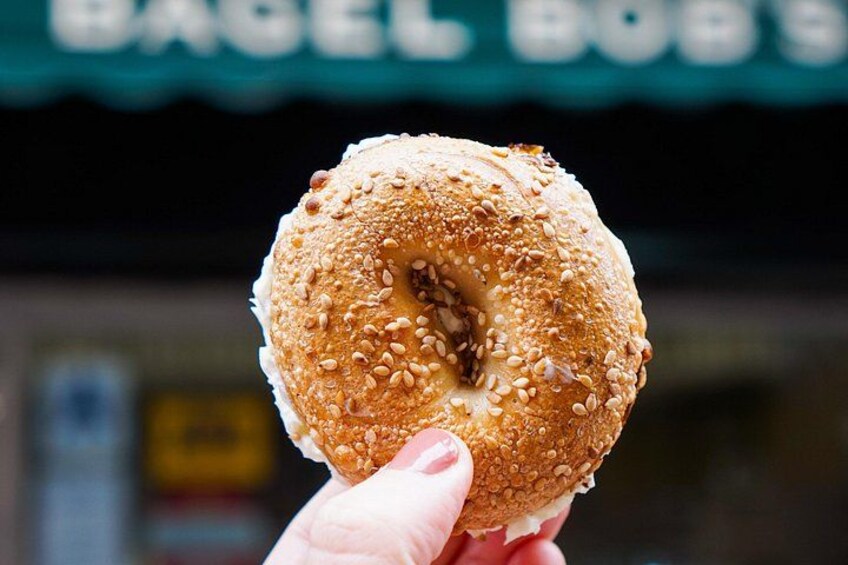 Una mano che tiene un bagel ai semi di sesamo con un morso. 5