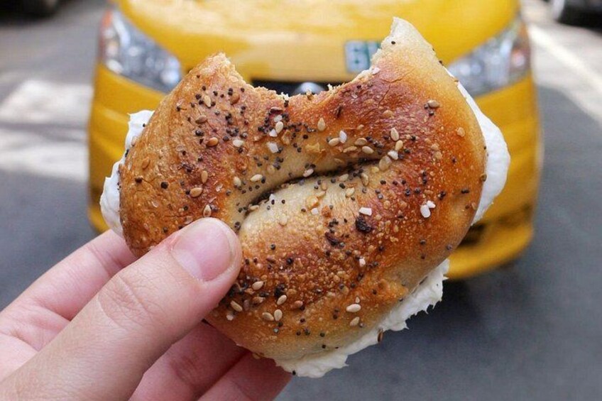 Una mano che tiene un bagel con semi di sesamo e semi di papavero. 4