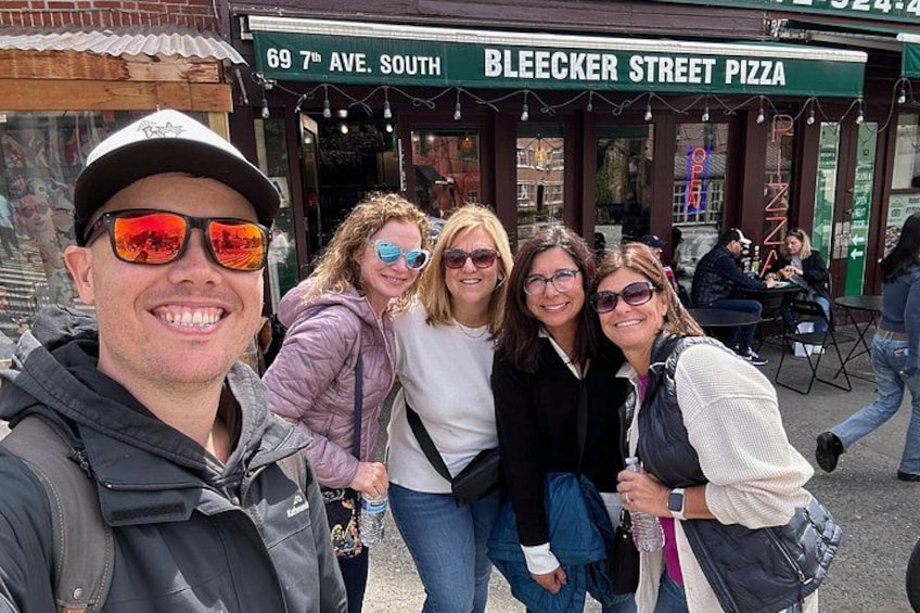 En grupp människor som poserar framför Bleeker Street Pizza. 2