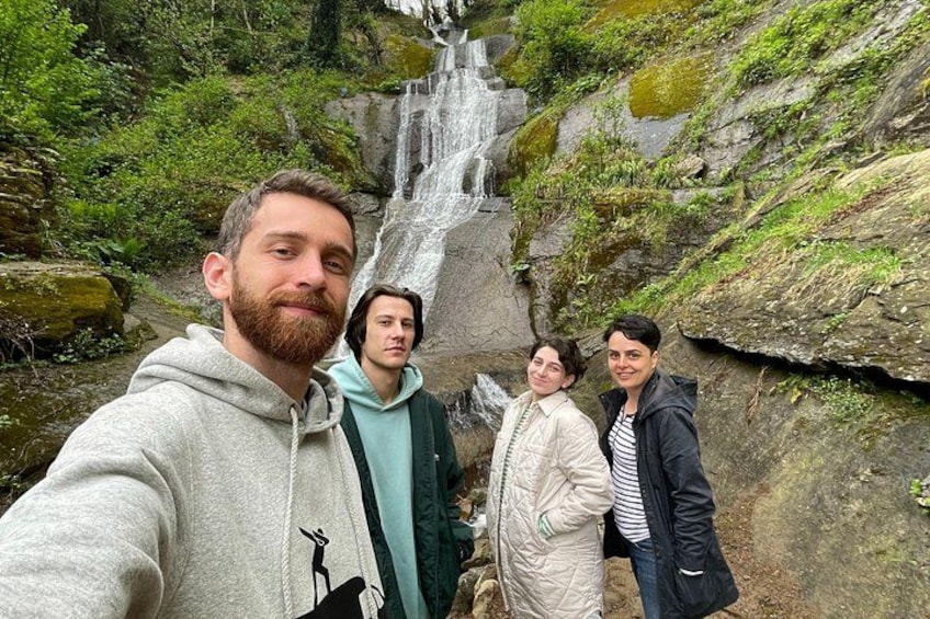 Een waterval, rotsachtig terrein en een groep mensen die een selfie maakt. 3