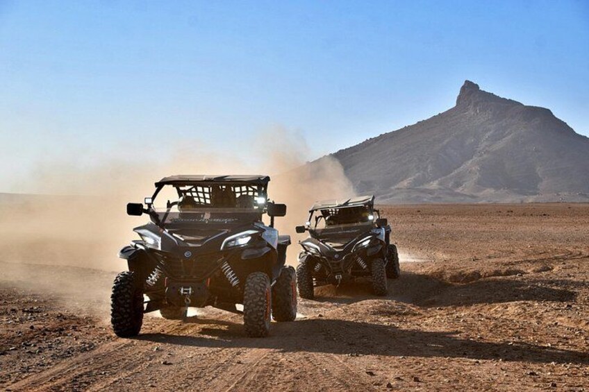 Two off-road vehicles on a dusty terrain with a mountain in the background. 5