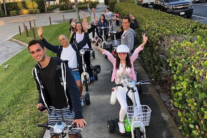 Een groep mensen rijdt op elektrische scooters over een voetpad. 2