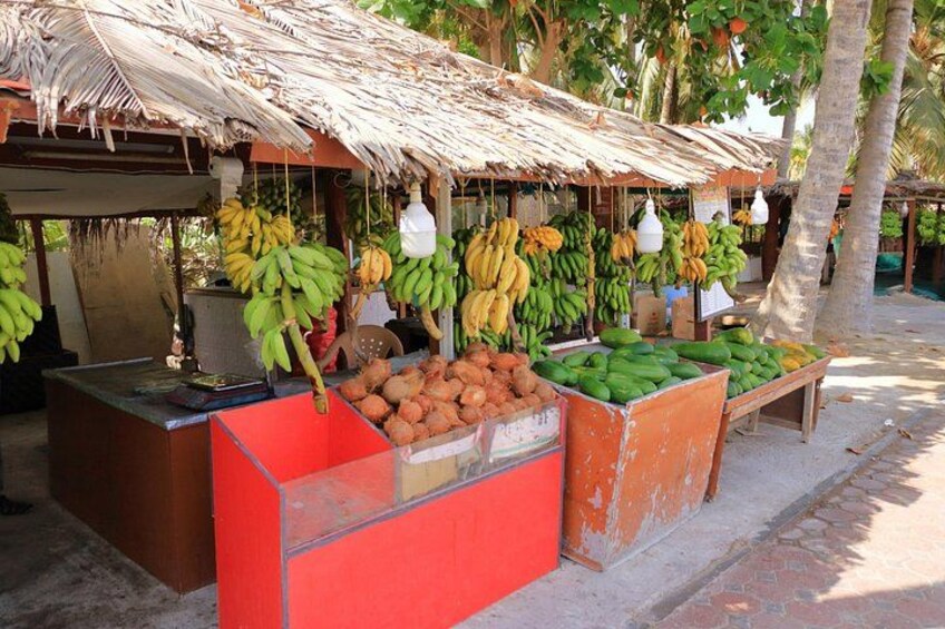 Un mercato di frutta con banane, noci di cocco e verdure verdi esposte su tavoli. 3