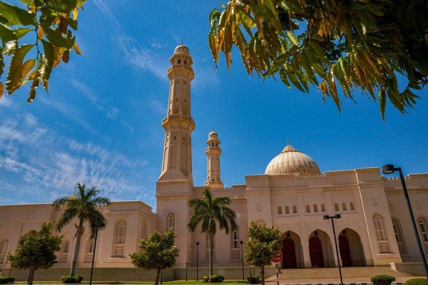 Una moschea con un minareto alto e una cupola, circondata da palme e un cielo azzurro intenso. 1