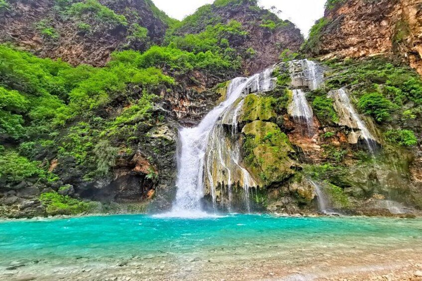 Una cascata che si getta in una piscina turchese circondata da vegetazione lussureggiante. 2