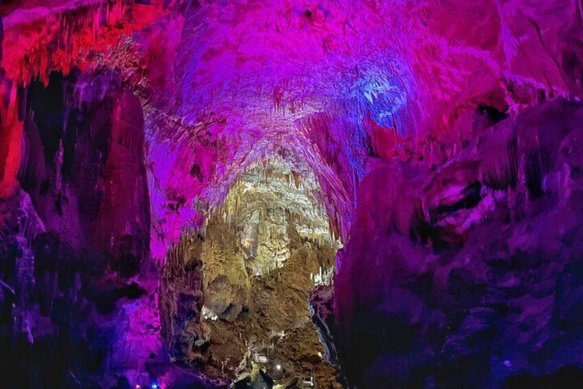En grotta med färgstark belysning och stalaktiter. 4