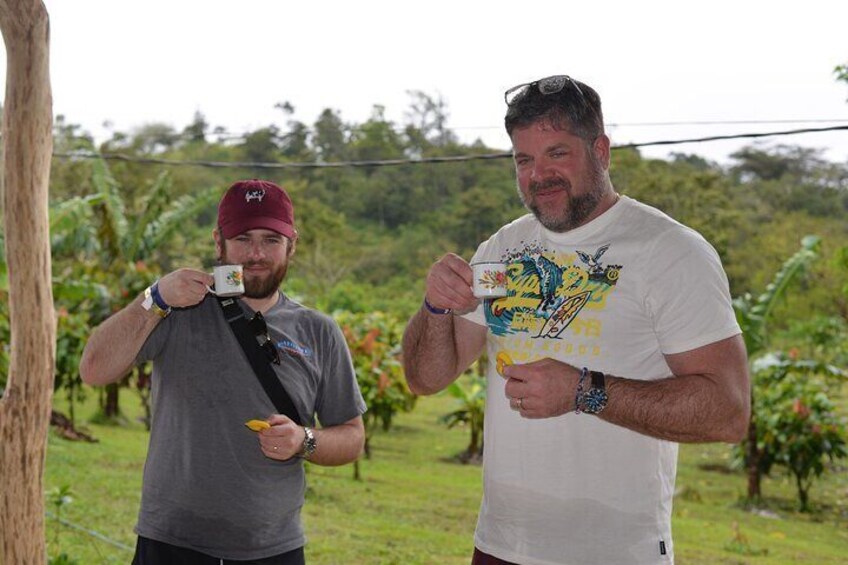 Two men in a vineyard holding cups, likely tasting wine. 3