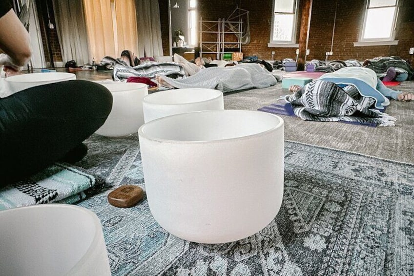 Un grupo de personas acostadas en el suelo de una habitación con lámparas grandes y blancas y una alfombra estampada. 1