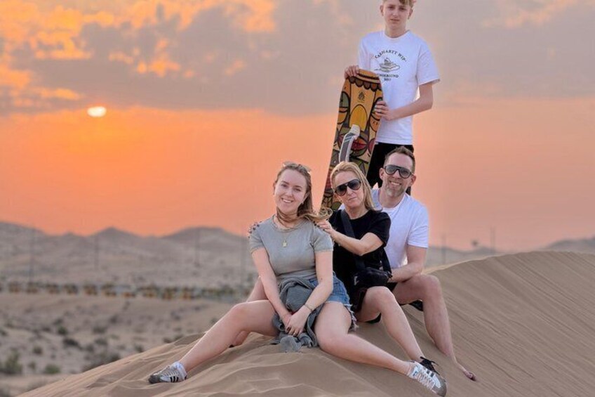 Tres personas en una duna de arena con un atardecer al fondo. 3