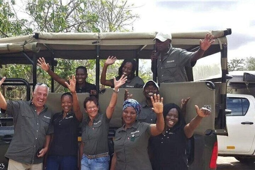 A group of people in safari attire posing in front of a vehicle. 3