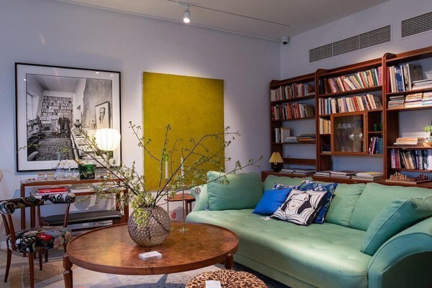 A living room with a green sofa, a round wooden coffee table, a bookshelf, and a framed picture on the wall. 1