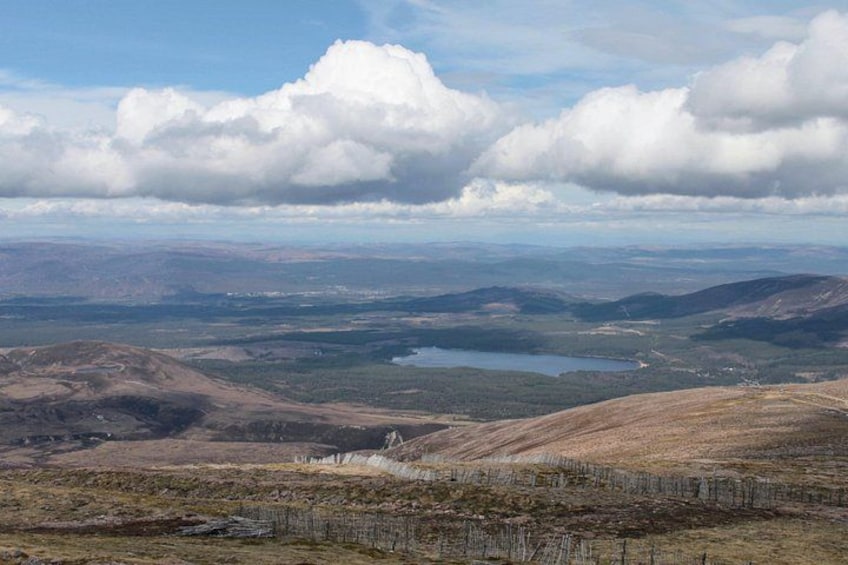 Un paysage montagneux avec un lac, des zones boisées et un ciel dégagé. 3
