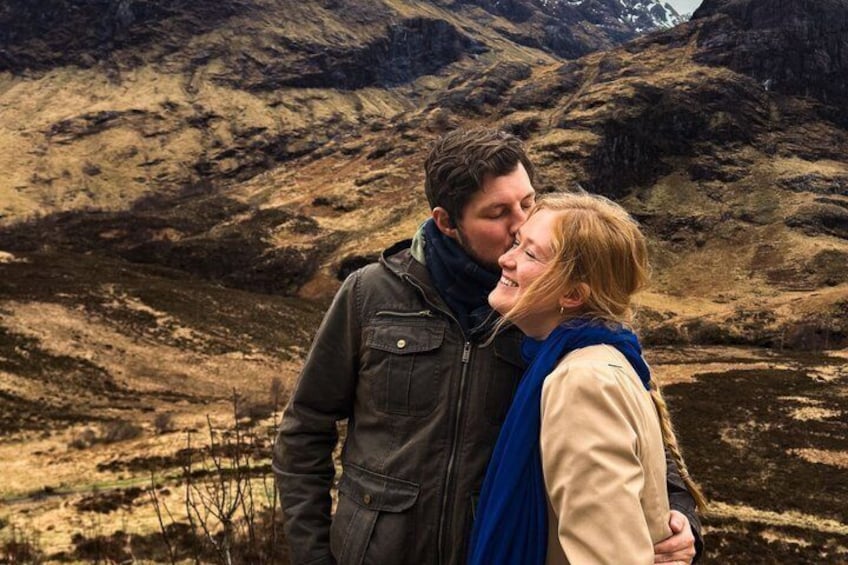Una pareja abrazándose en un paisaje montañoso con terreno rocoso y vegetación escasa. 5