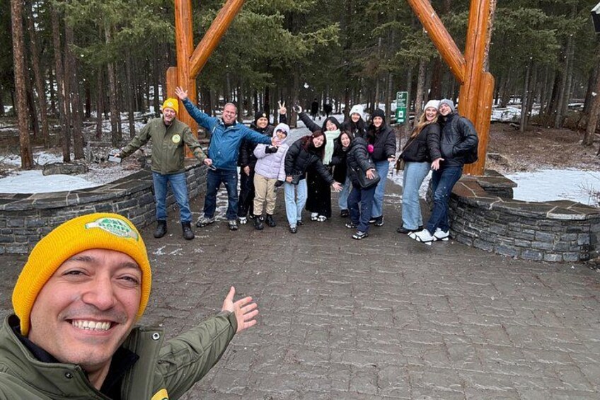 Un grupo de personas posando en un parque con una gran escultura de madera. 2