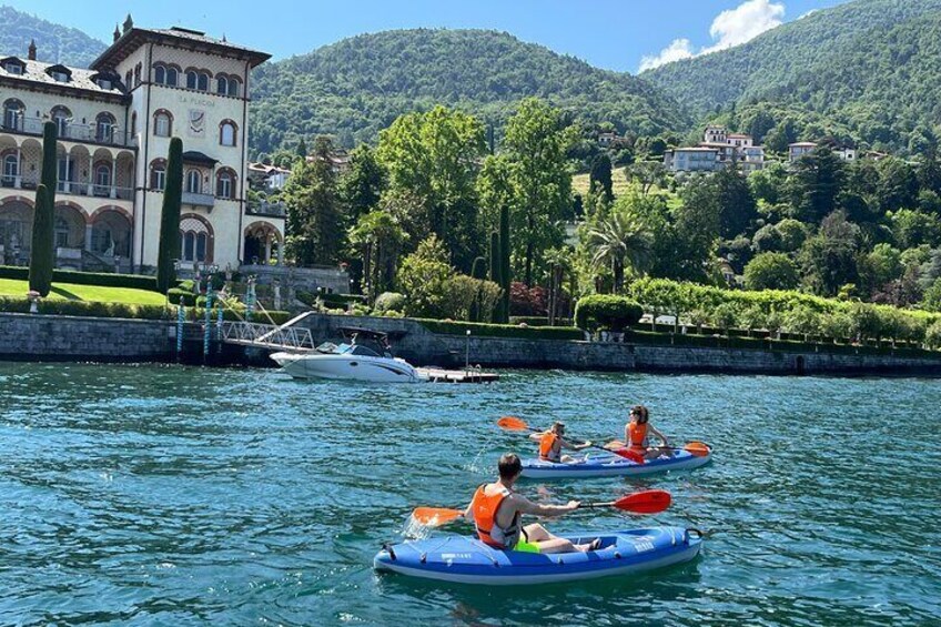 People kayaking on a lake with a large building and mountains in the background. 5