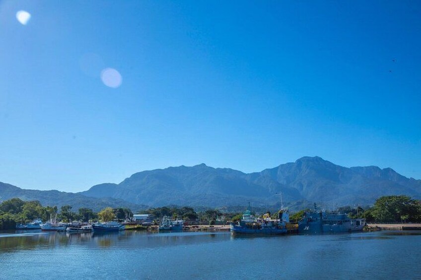 A calm river with boats, a clear sky, and mountains in the background. 4