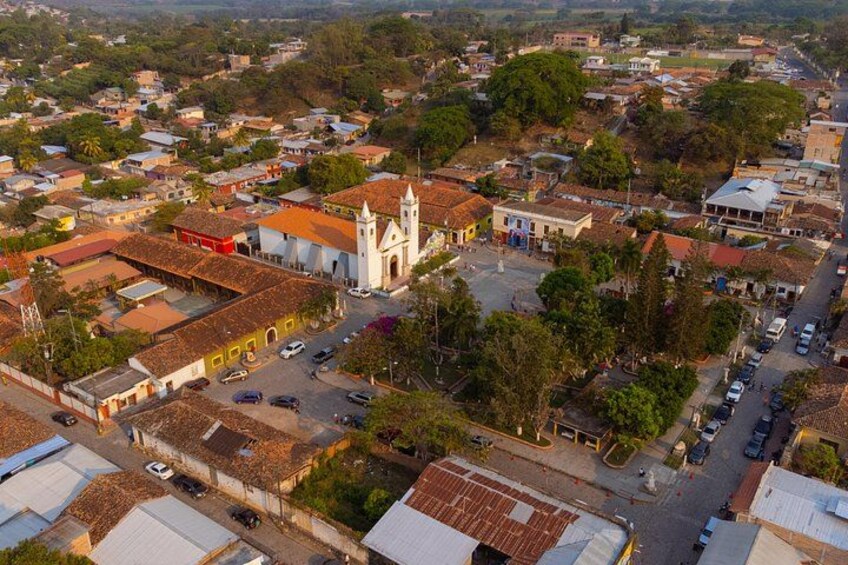 A town with a prominent church, a mix of residential and commercial buildings, and a central road. 2