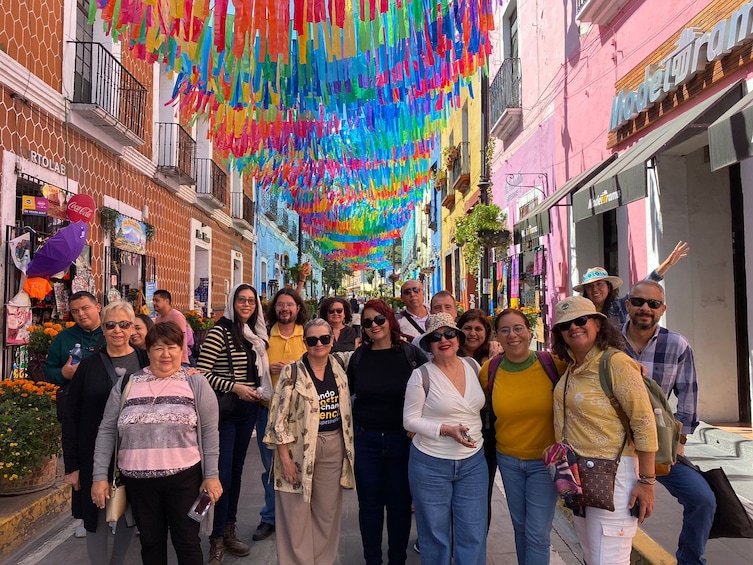 A group of people standing on a street with colorful decorations hanging overhead. 5
