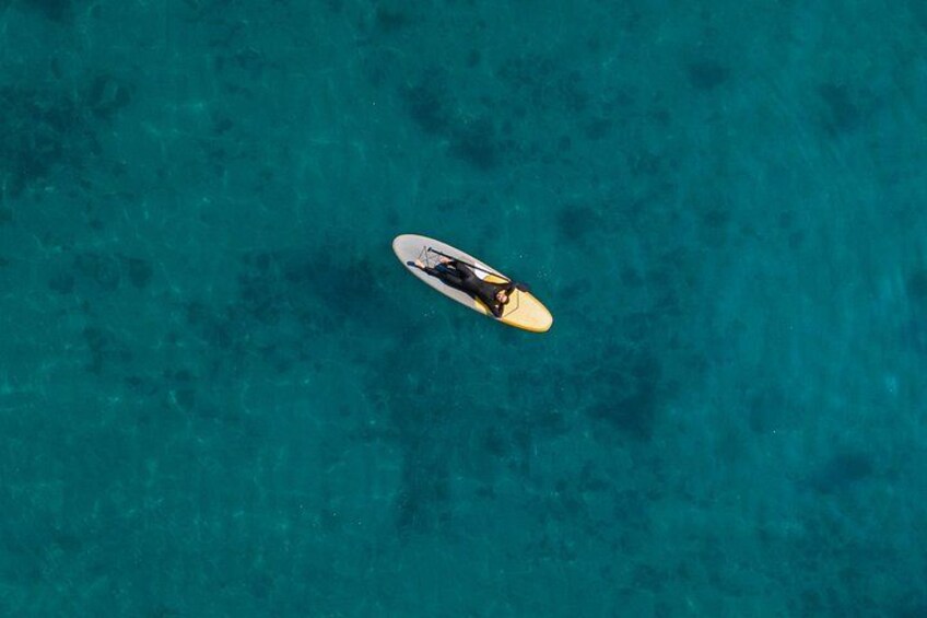 A person on a paddleboard in clear turquoise water. 3