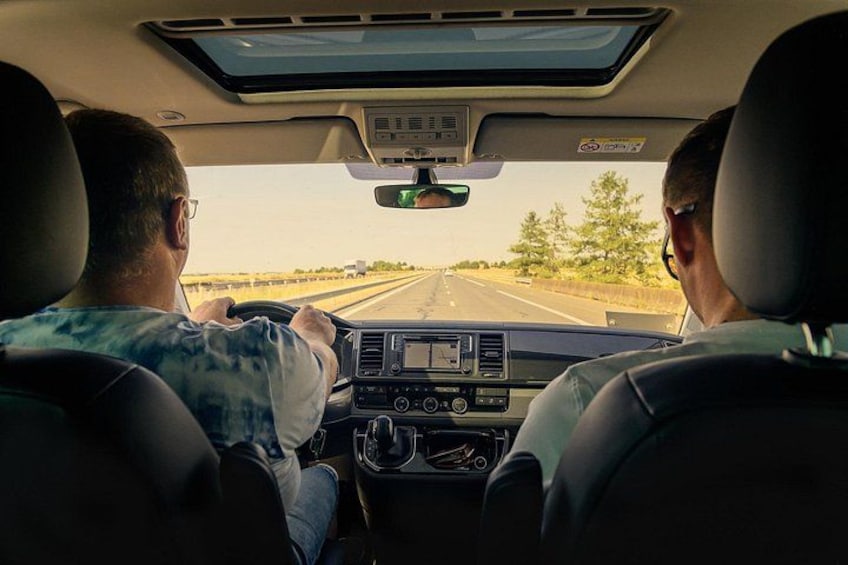 A vehicle interior with two people driving, a sunroof, and a dashboard with a GPS. 2