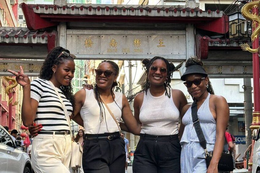 Four people standing in front of a traditional gate with Chinese characters. 5