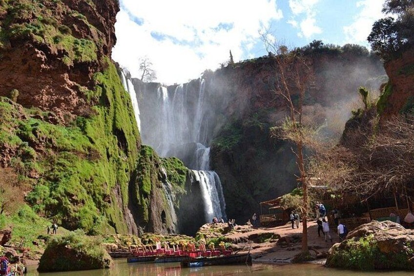 Una cascada rodeada de follaje verde y un pequeño bote al frente. 2
