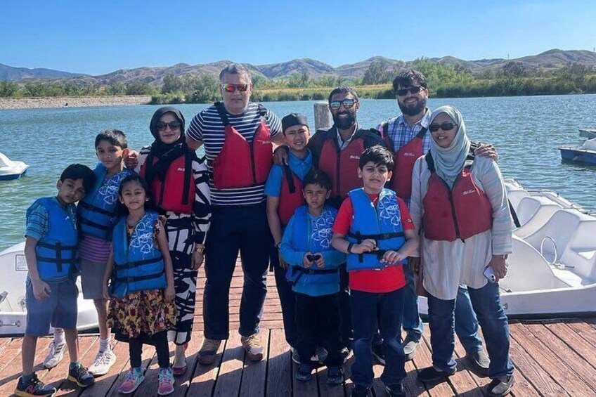 A group of people on a boat with a lake and mountains in the background. 2