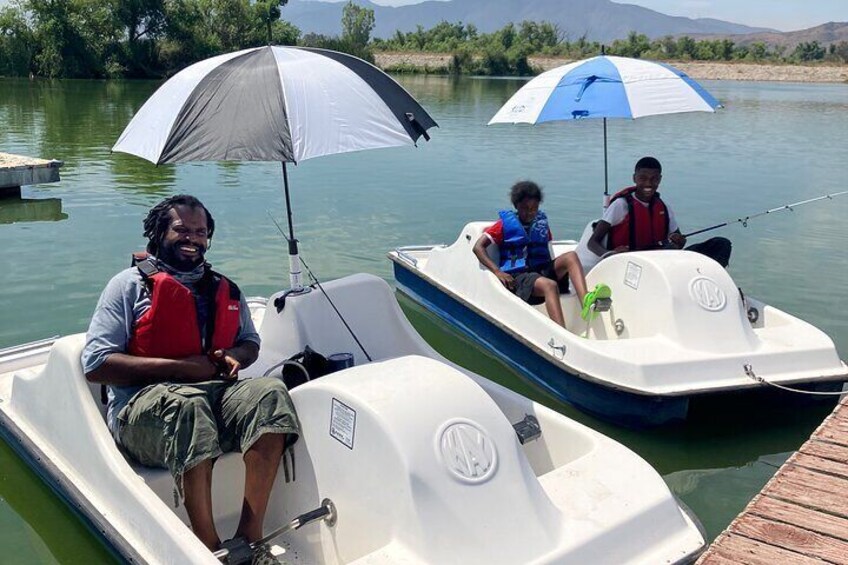 Two small boats on a calm river with people sitting under umbrellas. 3