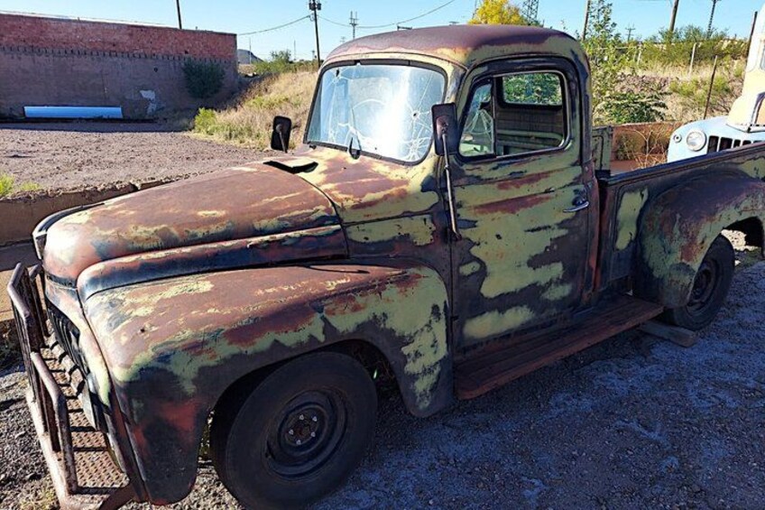 An old, rusted pickup truck parked on a gravel surface. 4